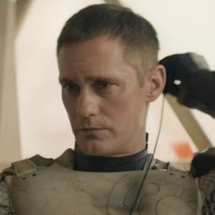 A focused man adjusts his gear, wearing a fitted outfit and armor. The background is softly blurred, suggesting a futuristic setting.