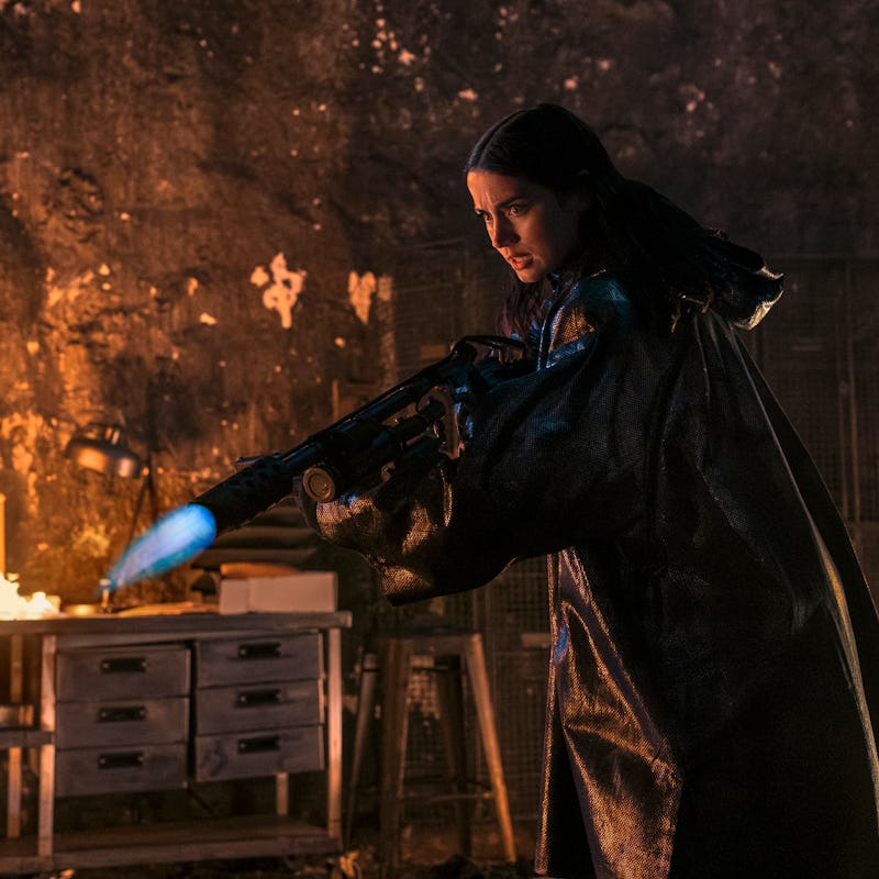 A figure in dark attire holds a weapon emitting flames, surrounded by a fiery backdrop in a dimly li...