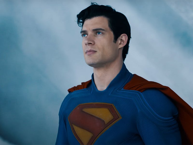 A man in a blue superhero costume with a red cape stands heroically, facing forward, with a determin...