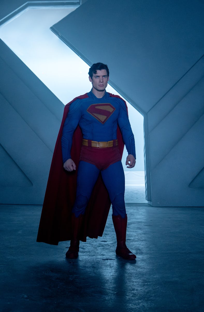 A superhero stands heroically in a futuristic, icy setting with crystalline formations and a large, ...
