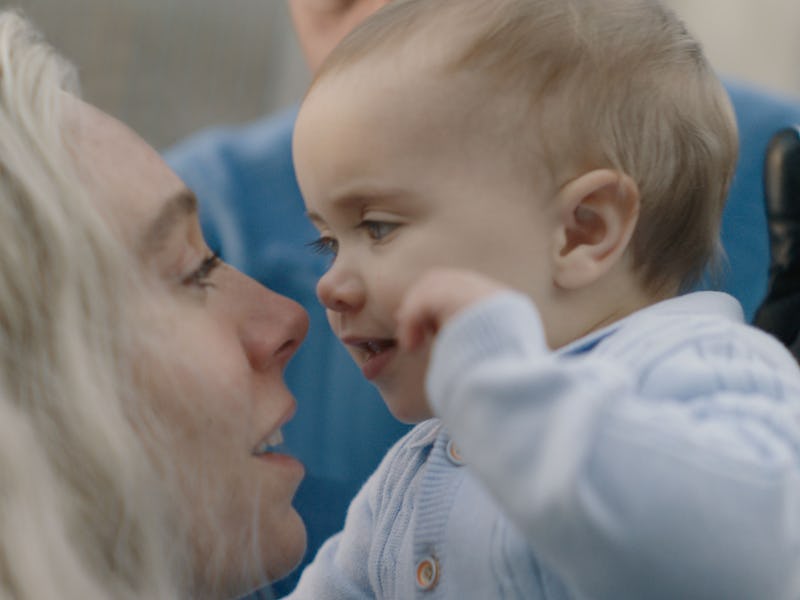 A close-up shot of a woman with long, light hair joyfully interacting with a smiling baby. Both shar...