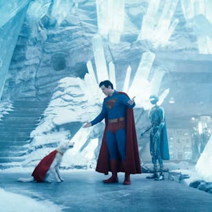 Superman stands in a crystalline, icy environment with a white cat and a futuristic figure, surrounded by tall ice formations and a staircase.