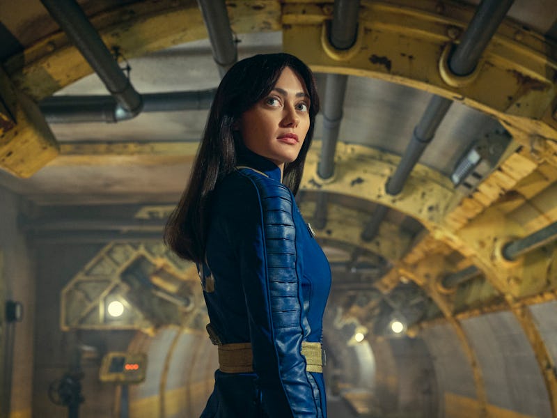 A person in a blue futuristic outfit stands confidently in an underground tunnel, with industrial pi...