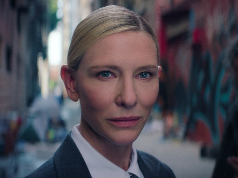 A woman in a tailored suit stands confidently in an urban alley, with colorful graffiti on the walls...
