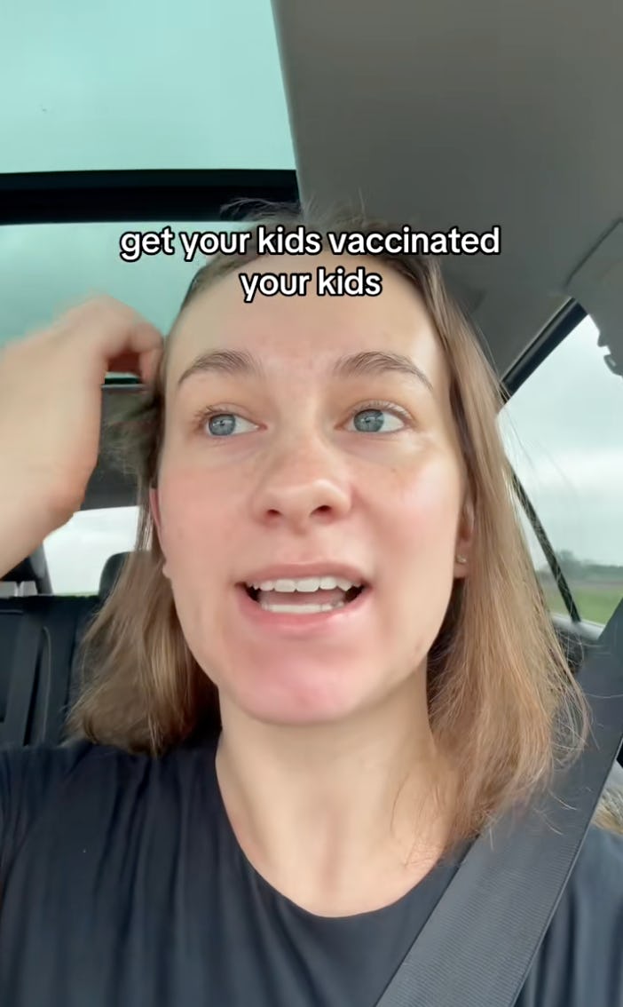 A person in a car is speaking with a serious expression, urging viewers to get their kids vaccinated. Their hair is slightly tousled, and the interior of the car is visible.