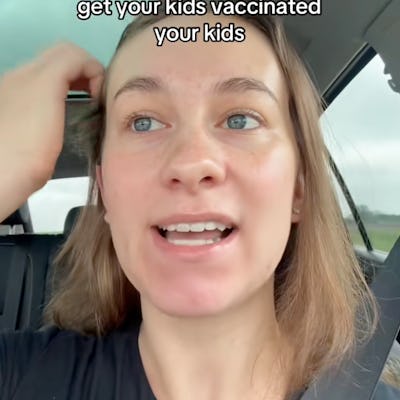 A person in a car is speaking with a serious expression, urging viewers to get their kids vaccinated. Their hair is slightly tousled, and the interior of the car is visible.