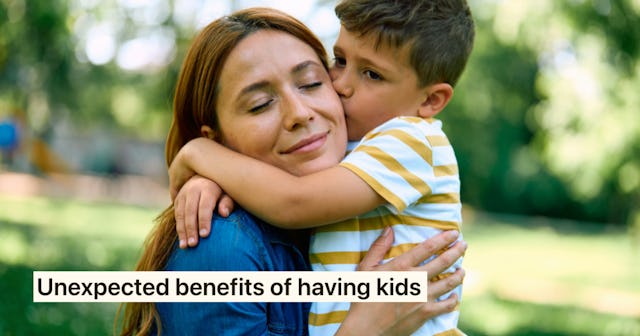 A smiling woman embraces a young boy in a park. The boy kisses her cheek, showcasing a warm and lovi...
