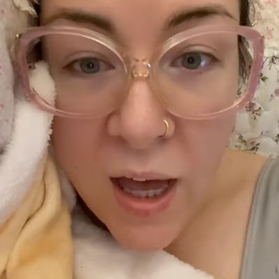 A close-up of a person with transparent glasses, lying in bed surrounded by a soft blanket, conveying a message of reassurance captioned "YOU'LL BE OKAY."