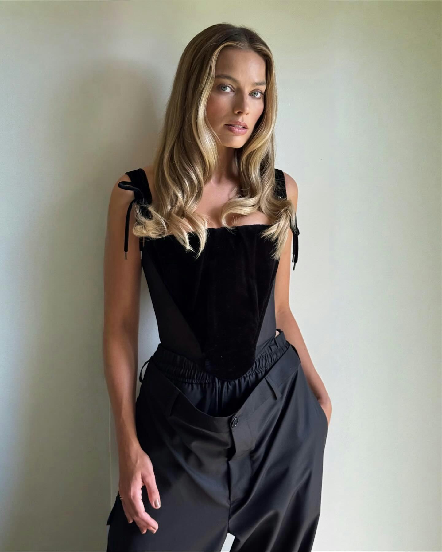 Margot Robbie wears a bustier and pants.