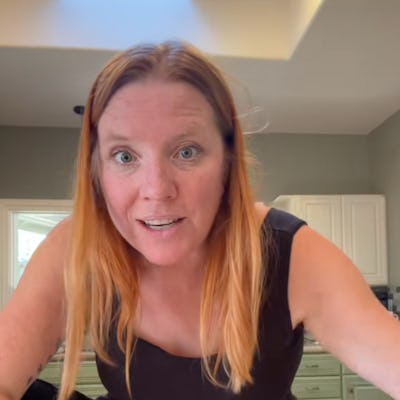 A woman with long red hair smiles while leaning over a table, looking surprised. Text below her reads, "THE WORST GRADE." A kitchen decorates the background.