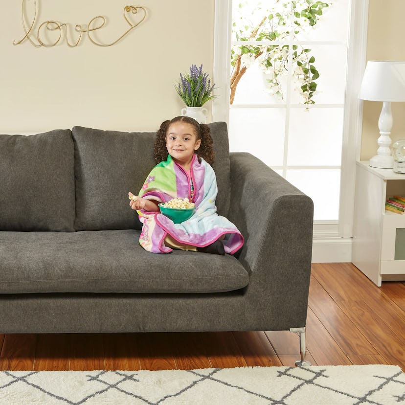 girl sitting on couch eating popcorn covered in Everyday Kids Toddler Throw Blanket