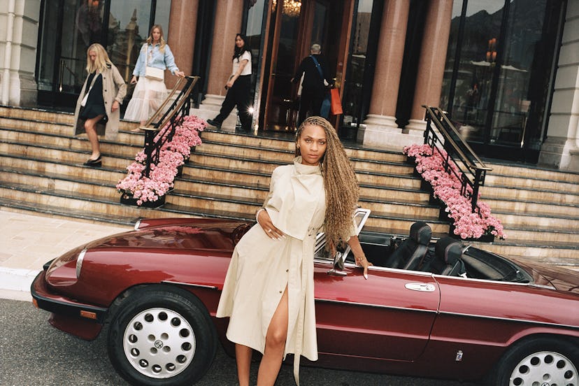 Ayan Broomfield stands in front of a vintage red convertible in France