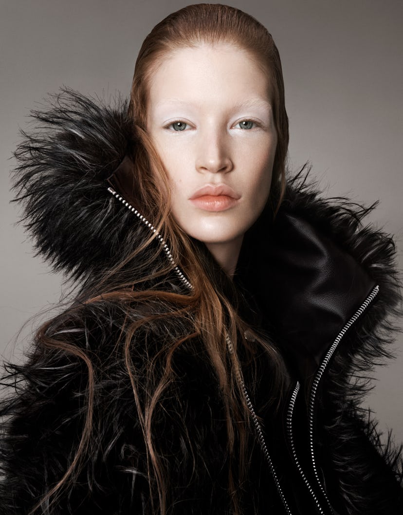 a model wearing a black jacket with feathers