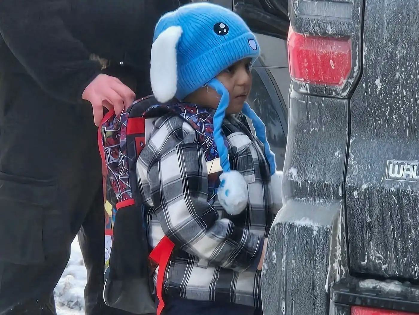 Liam Conejo Ramos, 5, being held by an ICE officer near the rear of an unmarked vehicle.