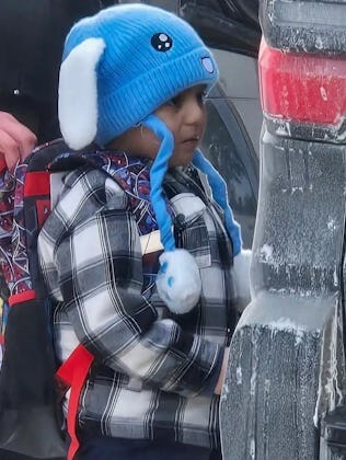 Liam Conejo Ramos, 5, being held by an ICE officer near the rear of an unmarked vehicle.