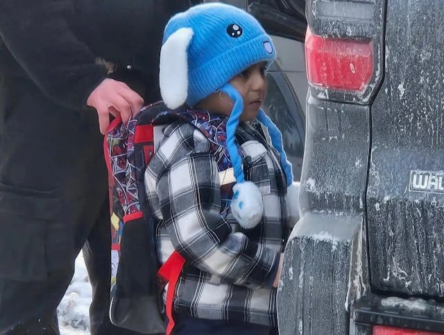 Liam Conejo Ramos, 5, being held by an ICE officer near the rear of an unmarked vehicle.