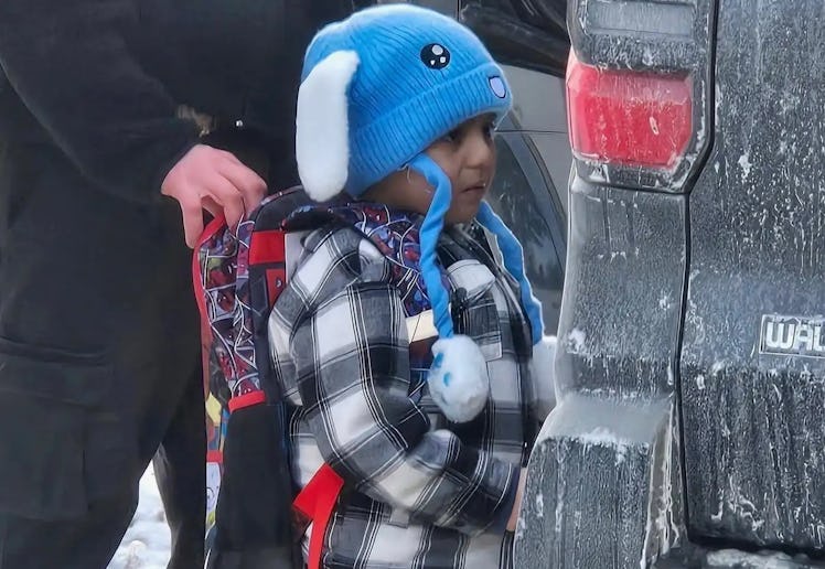 Liam Conejo Ramos, 5, being held by an ICE officer near the rear of an unmarked vehicle.