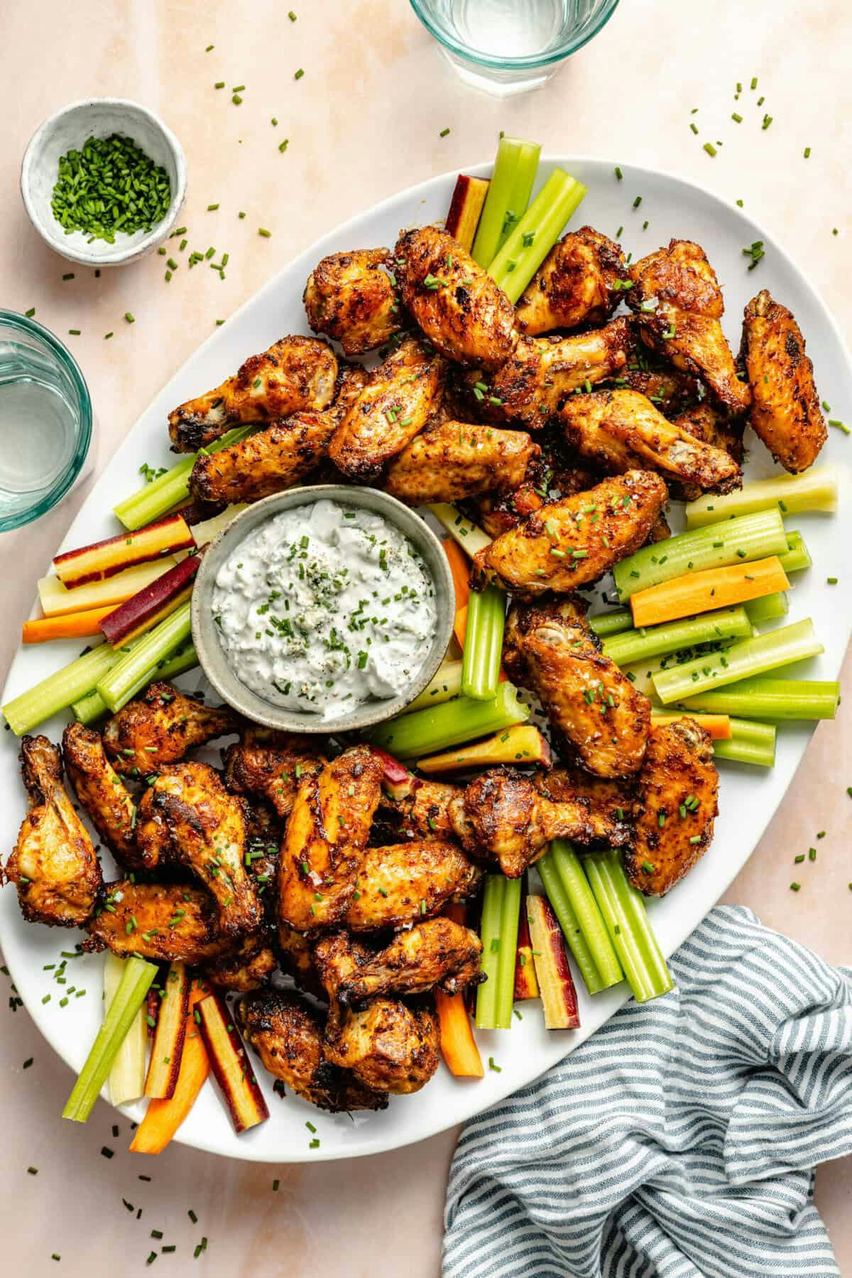 dry rub wings with celery and dip on a platter, in a story about easy super bowl appetizers and snac...