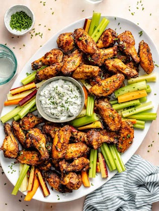 dry rub wings with celery and dip on a platter, in a story about easy super bowl appetizers and snac...