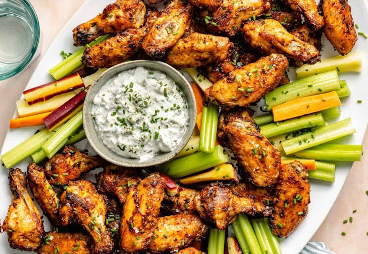 dry rub wings with celery and dip on a platter, in a story about easy super bowl appetizers and snac...
