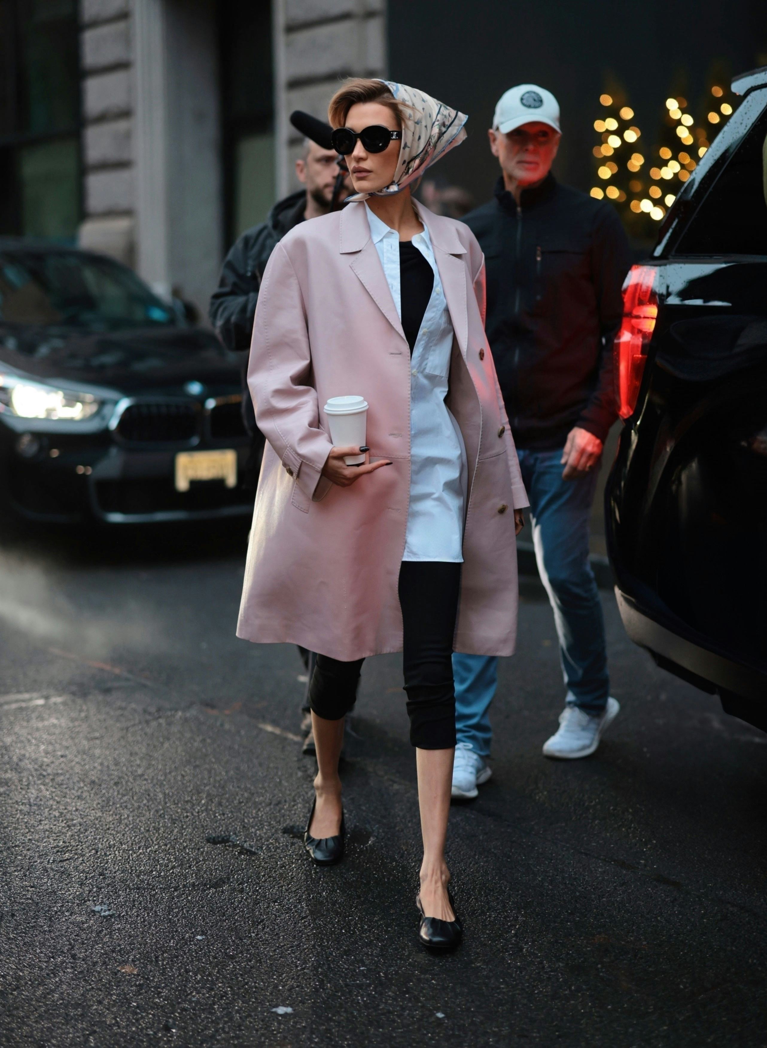Bella Hadid wears a pink leather coat, capri pants, and babushka.  