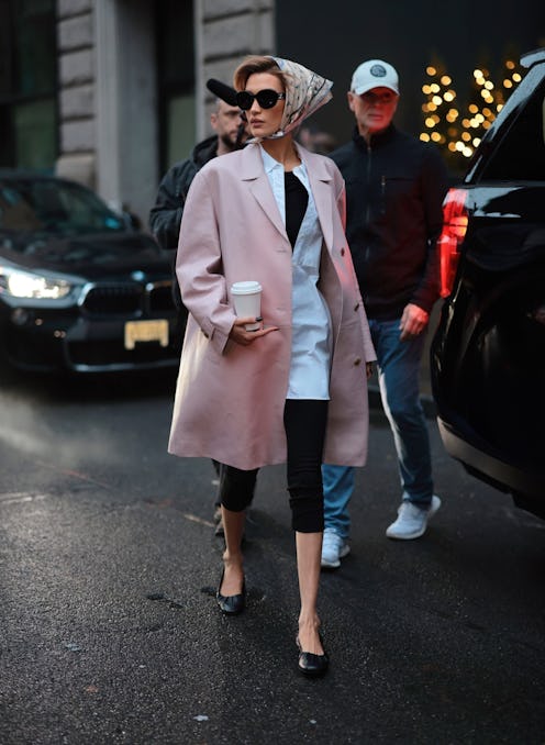 Bella Hadid wears a pink leather coat, capri pants, and babushka.