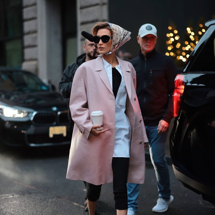 Bella Hadid wears a pink leather coat, capri pants, and babushka.