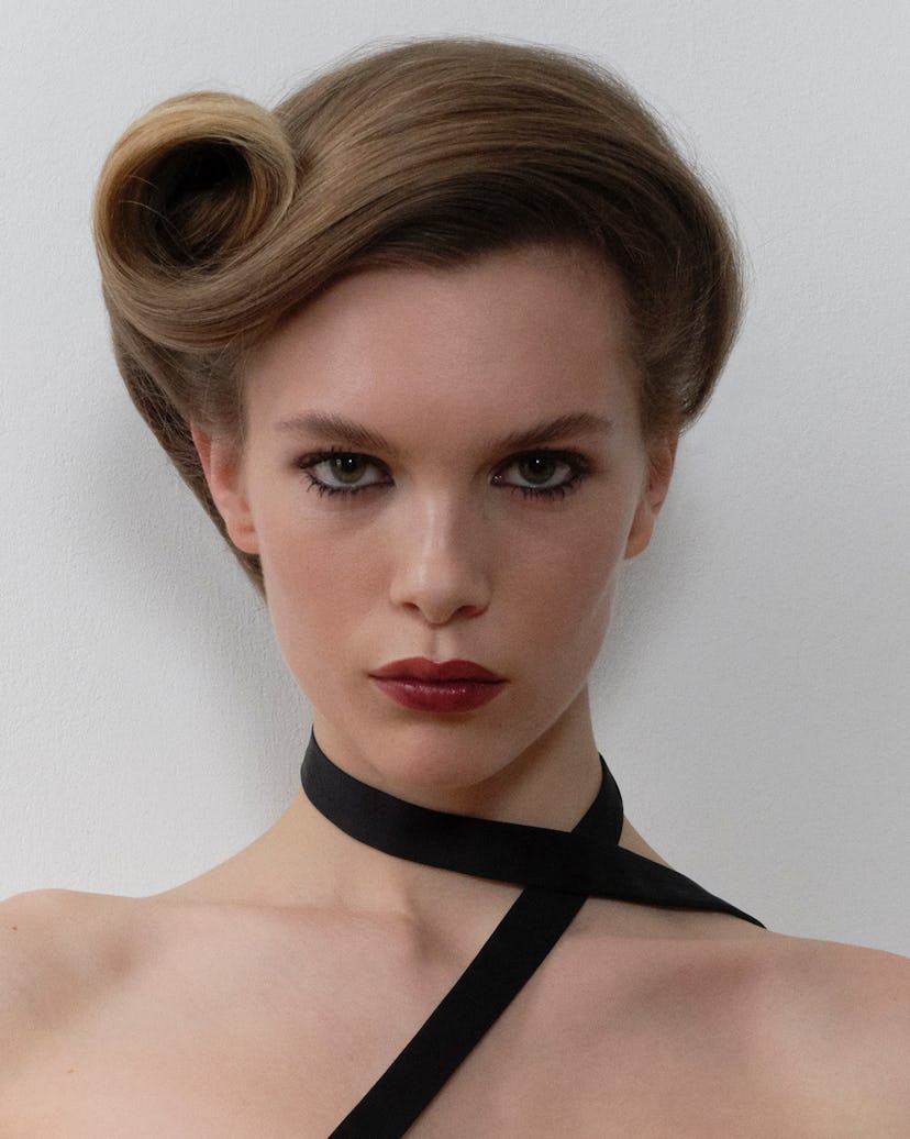 a person with red lipstick and their blonde ahir done in a smooth, round victory curl updo