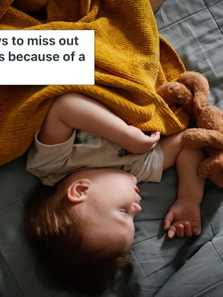 A toddler sleeps on a bed, wrapped in an orange blanket.