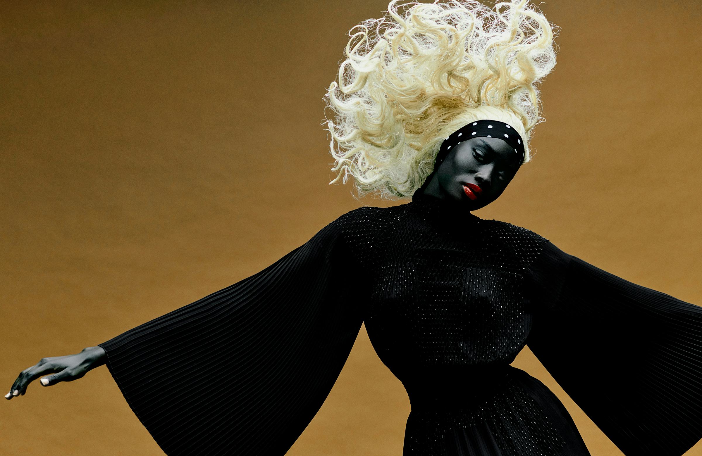 a model with a polka dot headband and big blonde gravity defying wig