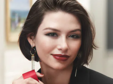 Model wearing Parisian Red Bobbi Brown lipstick, holding a ribbon