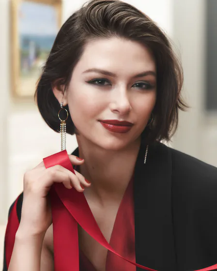 Model wearing Parisian Red Bobbi Brown lipstick, holding a ribbon