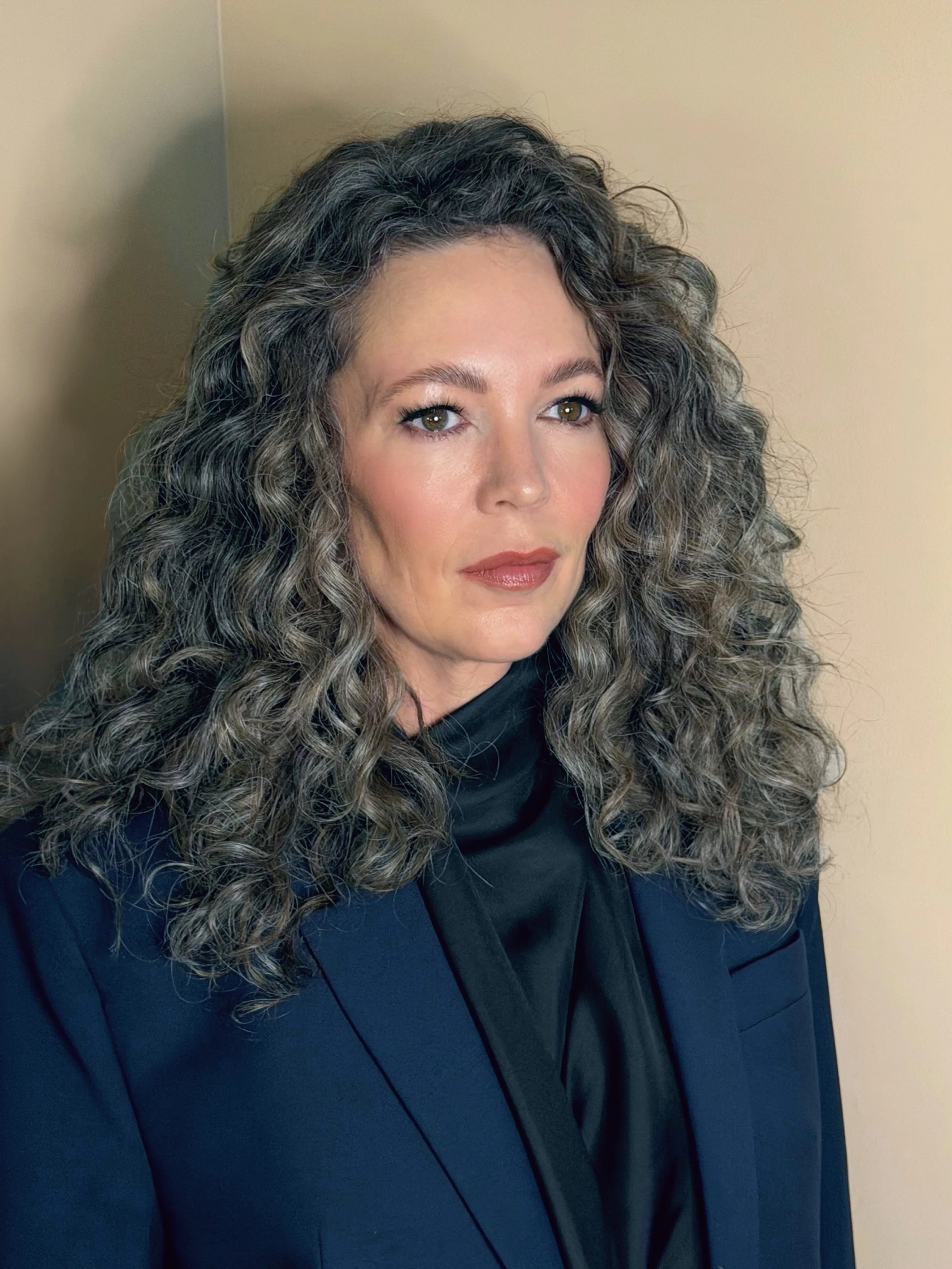 Olivia Colman with curly gray hair wearing a blue blazer