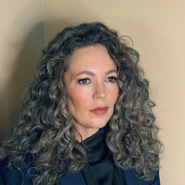 Olivia Colman with curly gray hair wearing a blue blazer