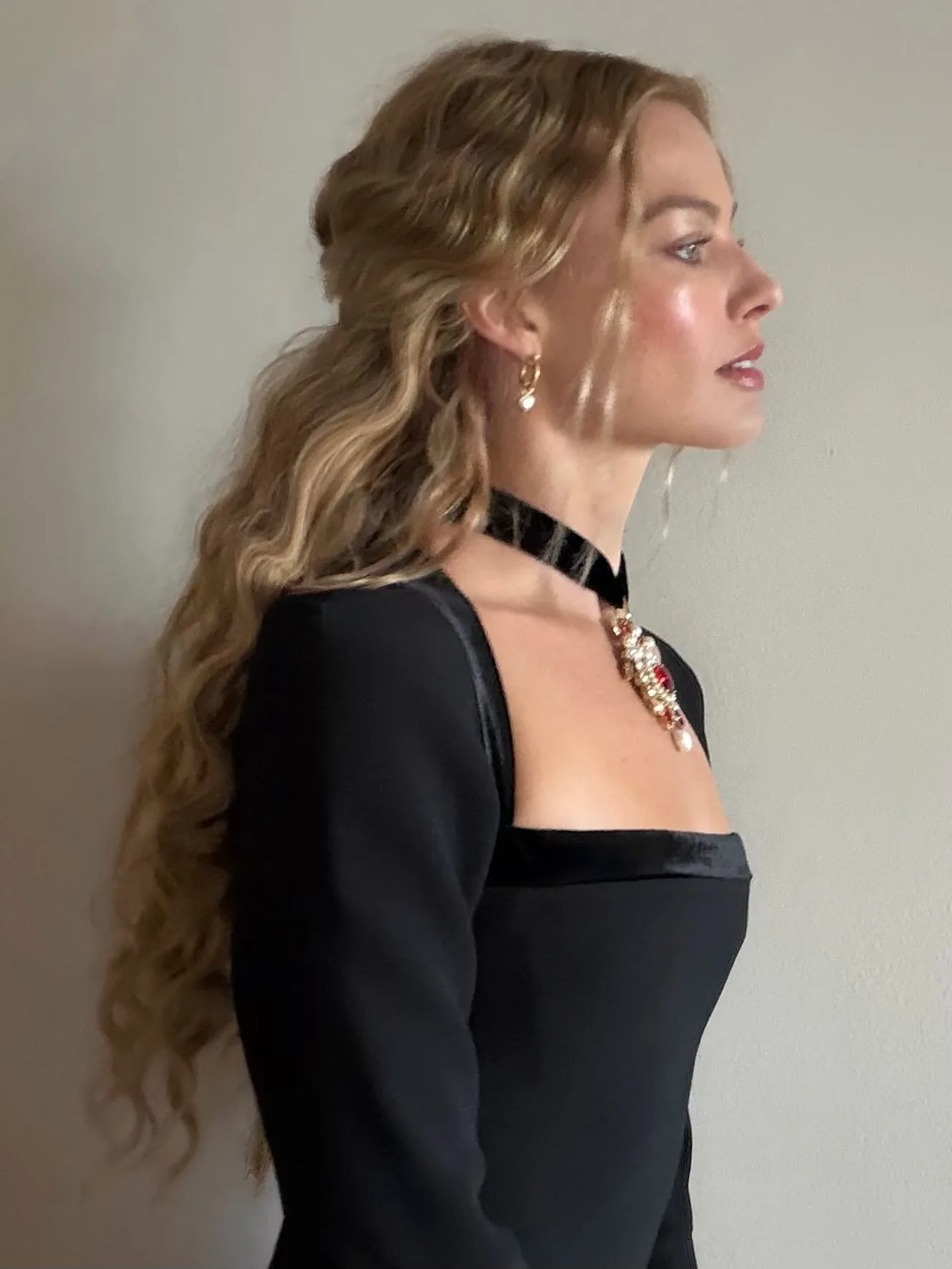 Margot Robbie in side profile, wearing loose waves