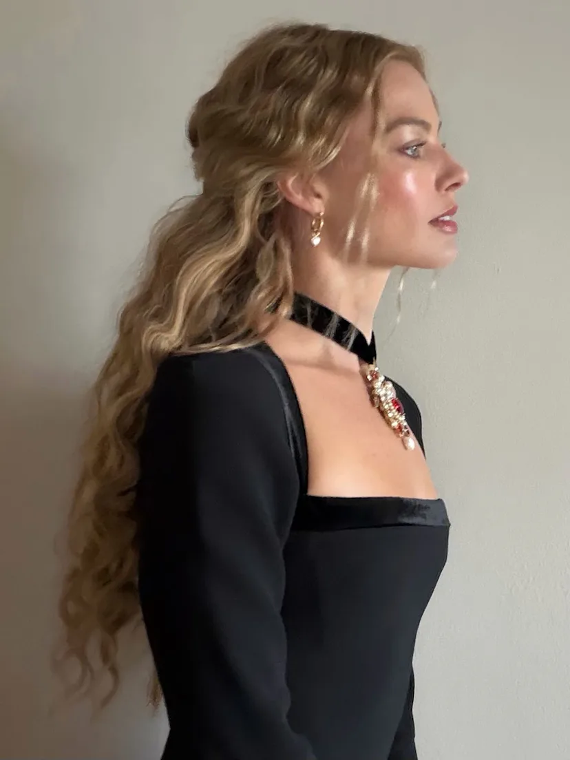 Margot Robbie in side profile, wearing loose waves