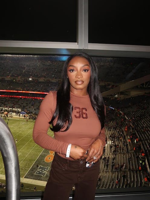 Simone Biles posing in front of a football field
