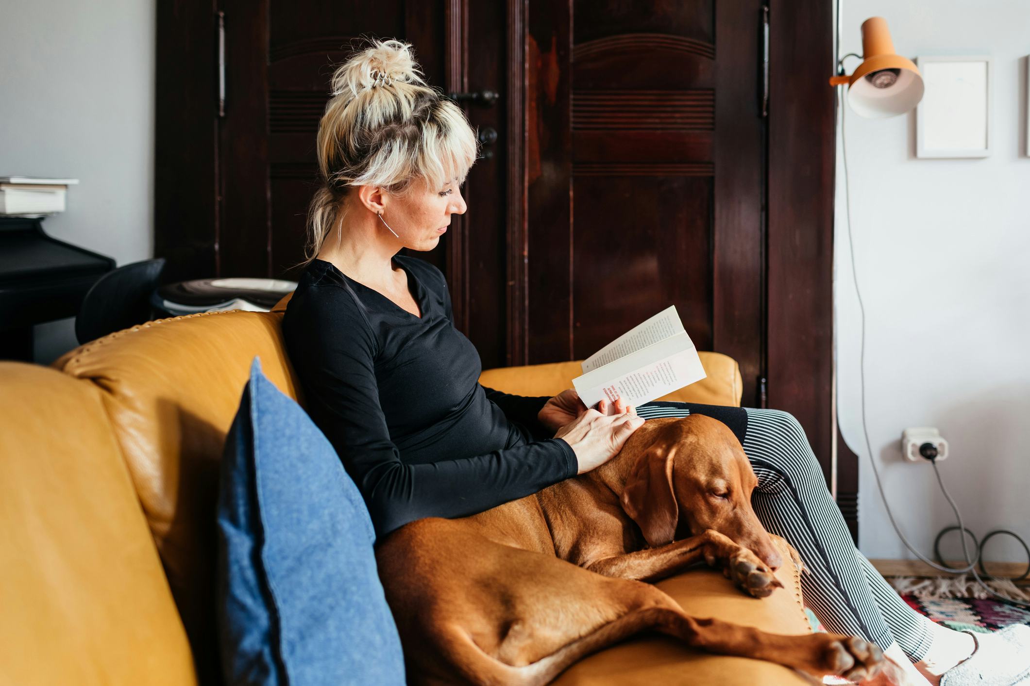 woman reading book with dog 