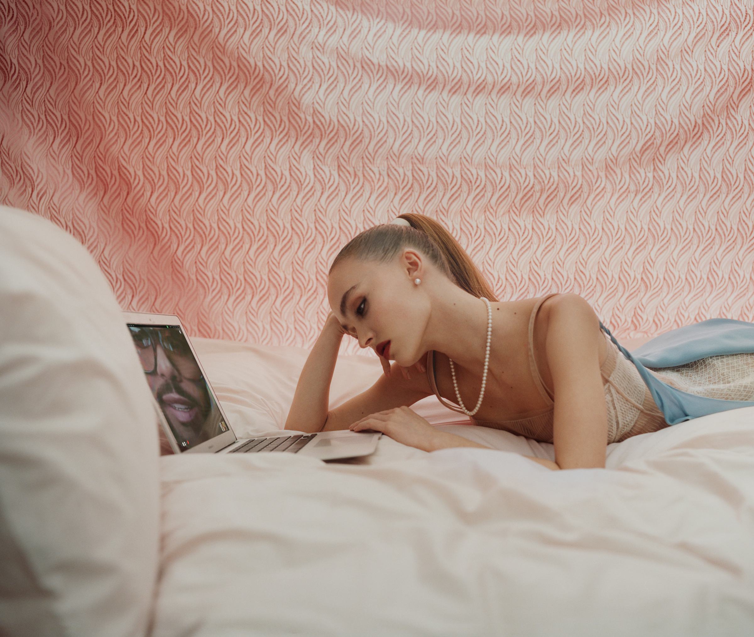 Lily Rose Depp laying in bed on her laptop