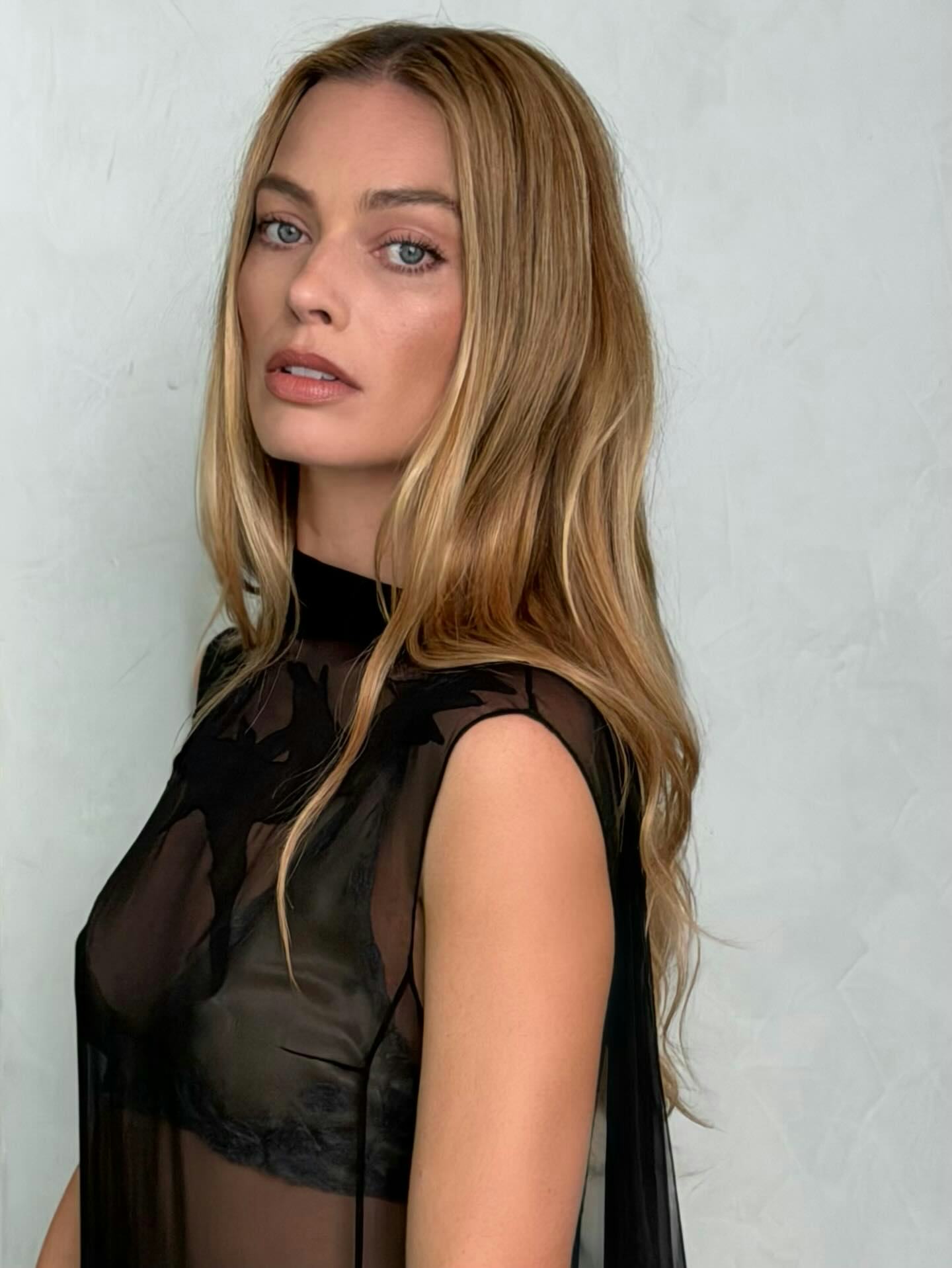Margot Robbie, looking over her shoulder, with long blonde hair