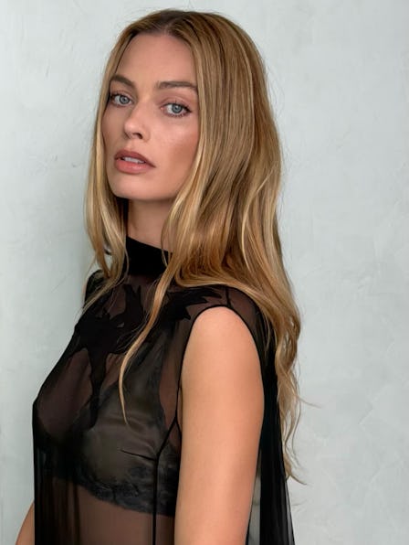 Margot Robbie, looking over her shoulder, with long blonde hair
