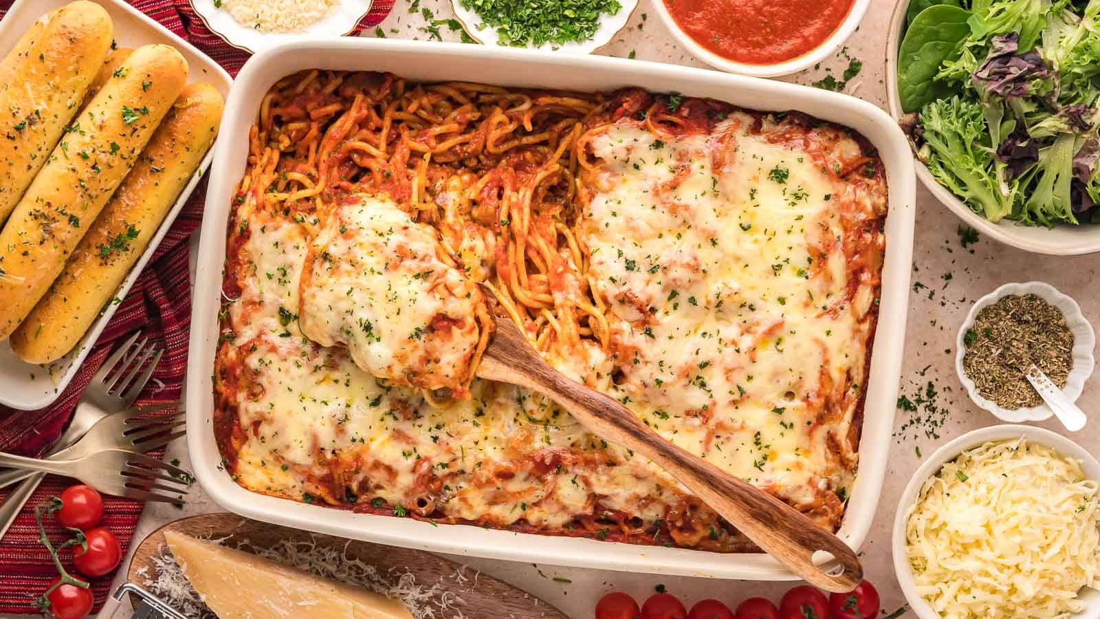 baked spaghetti surrounded by breadsticks and salad, a great recipe if you need kid dinner ideas