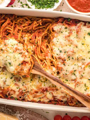 baked spaghetti surrounded by breadsticks and salad, a great recipe if you need kid dinner ideas