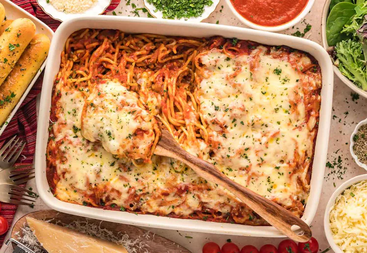 baked spaghetti surrounded by breadsticks and salad, a great recipe if you need kid dinner ideas