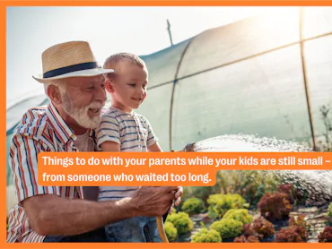 A grandfather and his grandson water the garden.