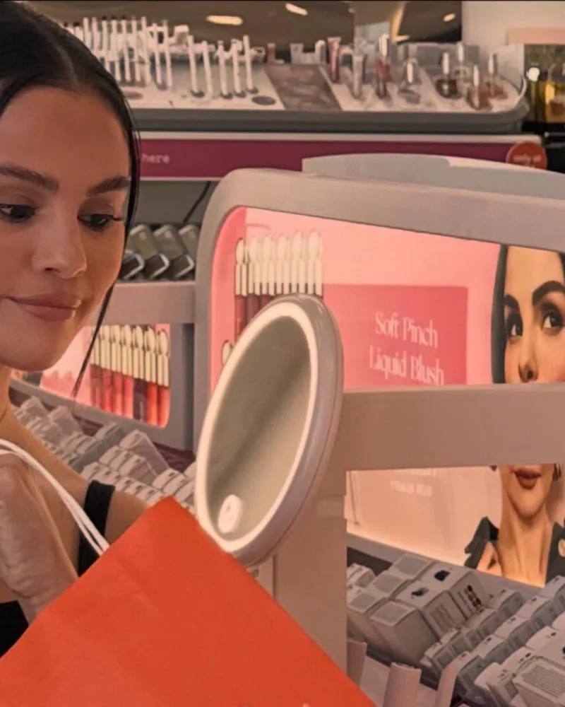 Selena Gomez wearing a center-parted bun with face-framing pieces at Ulta