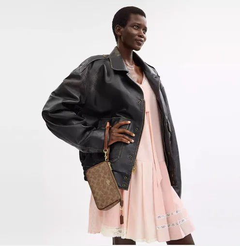 Ready for graduation, a woman is holding a small Nolita 19 bag in wristlet form.