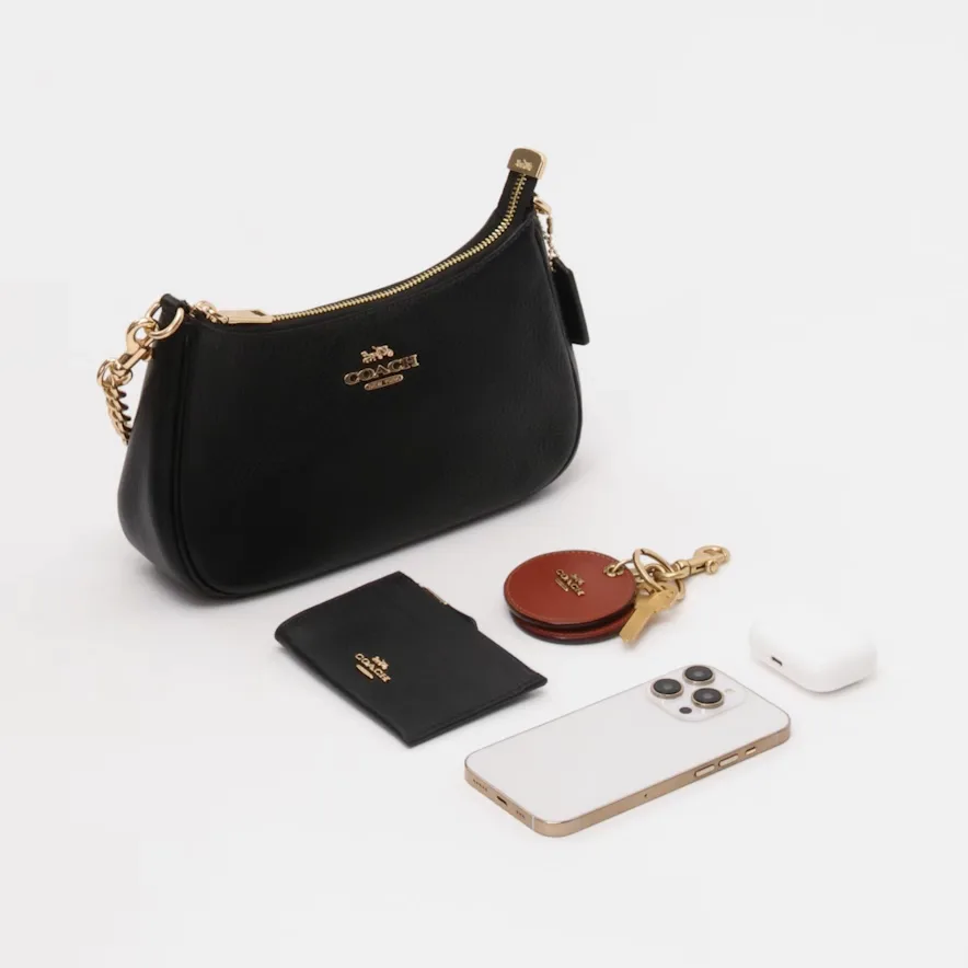 A black Teri bag with the items that fit neatly inside, including an iPhone 17.