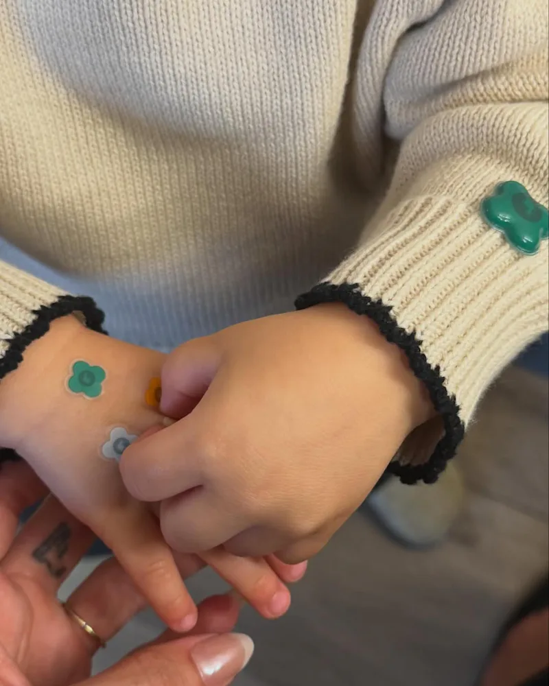 Hailey Bieber, holding her son's hand, her French tip chrome mani visible