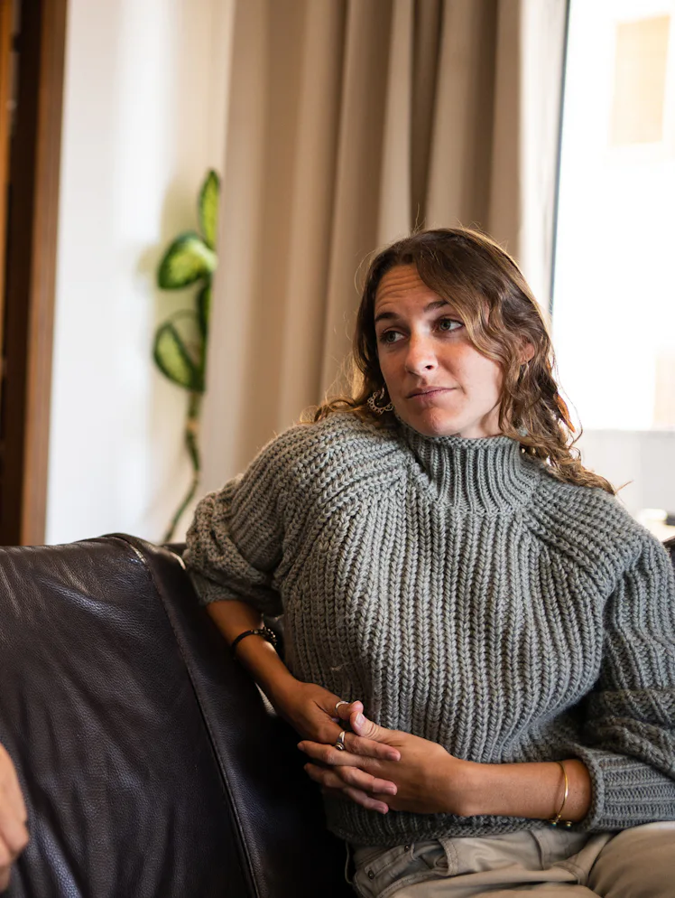 A man and woman are sitting on a couch in a living room. The man is speaking while the woman listens...